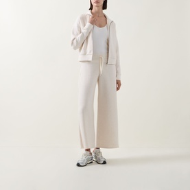 Model wearing Spanx AirEssentials&reg; Track Jacket in Oatmeal Heather with matching wide-leg trousers, white vest, and grey trainers.