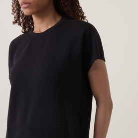 Model wearing Spanx AirEssentials T-Shirt in Very Black with crew neckline, short sleeves, and slightly cropped straight hem.