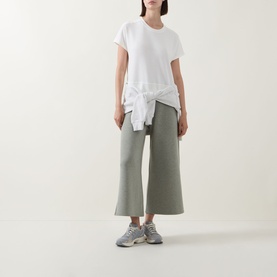 Model wearing Spanx AirEssentials&reg; T-Shirt in Powder with sage wide-leg cropped trousers and grey trainers.