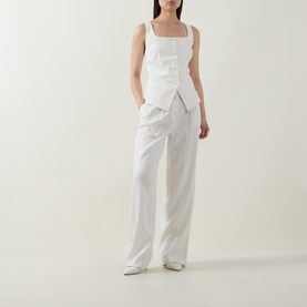 Model wearing Spanx ivory sleeveless square-neck top with asymmetric wrap detail, styled with wide-leg white trousers and white shoes.