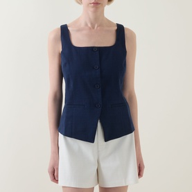 Model wearing Spanx Timeless Navy sleeveless top with square neckline and front button detail, styled with white shorts