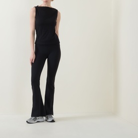 Model wearing Spanx Classic Black sleeveless top with matching black flared trousers and silver trainers