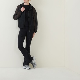 Model wearing Spanx Classic Black top with matching black flared trousers and grey chunky trainers, full-length shot