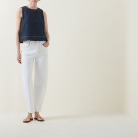 Model wearing Spanx Lightweight Denim Shell Tank in Deep Sea with white straight-leg jeans and flat sandals.
