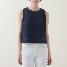 Model wearing Spanx Lightweight Denim Shell Tank in Deep Sea, with white jeans. Round neck, sleeveless, contrast topstitch details.