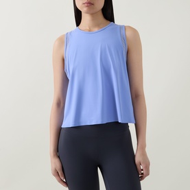 Model wearing Spanx Hyacinth active top, styled with navy leggings. Sleeveless relaxed-fit crop style with crew neck.