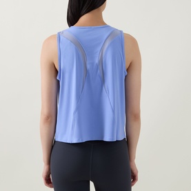 Model wearing Spanx Hyacinth active top, back view showing mesh panel cut-out detail, styled with dark navy leggings.