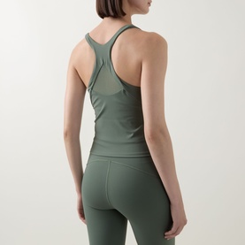 Model wearing Spanx BoostUp Shelf Tank in Eucalyptus, showing mesh racer-back detail, paired with matching leggings.