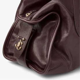 Close-up of burgundy leather bag with gold-tone hardware clasp detail and zip fastening