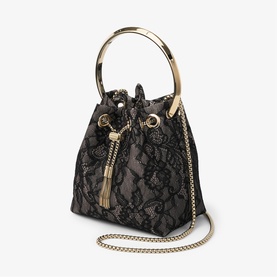 Black lace bucket bag with gold circular top handle, tassel drawstring, and gold chain crossbody strap