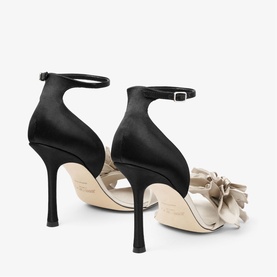 Jimmy Choo white satin heeled sandals with oversized bow detail, ankle strap, and stiletto heel, shown from rear angle.