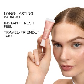 Model with Lanc&ocirc;me Highlighter in 04 Strawberry Glow Cream, holding travel-friendly tube close to face, showcasing radiant complexion finish