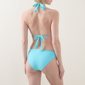 Model wearing Naia Beach Ursula Side-Tie Bikini Briefs in aqua with matching halterneck top, rear view showing tie fastenings.
