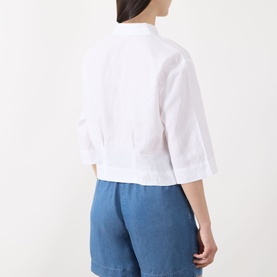 Model wearing Selected Femme Bright White linen-cotton cropped shirt, back view, styled with blue denim shorts.