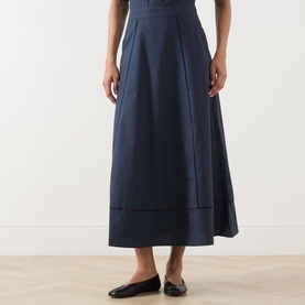 Model wearing Selected Femme Dark Sapphire cotton midi skirt with A-line silhouette and panel detailing, styled with black flat shoes.