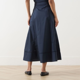 Model wearing Selected Femme Dark Sapphire cotton midi skirt with A-line silhouette and panelled hem, styled with black flats.
