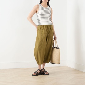 Model wearing Selected Femme Moon Striped Knitted Vest in Birch/Black Stripes, styled with olive midi skirt, black sandals, and neutral tote bag.