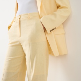 Model wearing Selected Femme Italian Straw trousers in viscose-linen blend, styled with matching yellow blazer, hands in pockets.