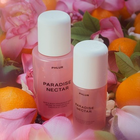 Phlur Paradise Nectar Hair and Body Mist in two sizes, pink bottles with white caps, styled with roses, orange fruits and petals.