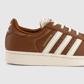 Adidas Superstar trainer in Dusky Bronze and Cream White, featuring leather upper, three cream stripes, and off-white shell toe sole