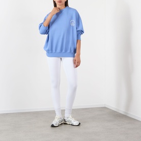 Model wearing Adanola Blossom Blue cotton sweat top with white leggings and chunky trainers.