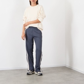 Model wearing Adanola Midnight Blue sweat bottoms with white side stripe, styled with a cream knit sweater and grey trainers.