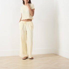 Model wearing Adanola ButterCream cotton T-shirt, cropped fit, styled with matching wide-leg trousers and tan sandals.