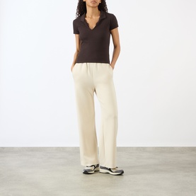 Model wearing Adanola Coffee Bean lace-trim V-neck top, styled with cream wide-leg trousers and grey trainers.