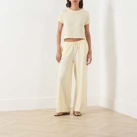 Model wearing Adanola ButterCream wide-leg cotton trousers with matching cropped tee and tan sandals