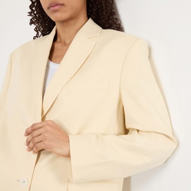 Model wearing Anine Bing Quinn Single-Breasted Blazer in butter yellow, notched lapels and padded shoulders visible, styled over white top.