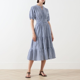 Model wearing Barbour Ashwell Gingham Tiered Dress in multi gingham with puff sleeves and tiered midi skirt, styled with brown sandals