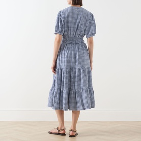 Model wearing Barbour Ashwell Gingham Tiered Dress in Multi Gingham, back view showing shirred waist and tiered midi skirt, styled with tan sandals