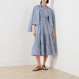 Model wearing Barbour Ashwell Gingham Tiered Dress in Multi Gingham with matching cropped jacket, styled with black strappy sandals.