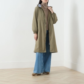 Model wearing olive green hooded parka coat, styled with striped turtleneck, wide-leg blue jeans and brown loafers