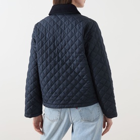Model wearing Barbour Aylesby Quilted Jacket in Dark Navy, back view, showing diamond quilting and corduroy collar, styled with light blue jeans.