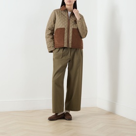 Model wearing Barbour Aylesby Quilted Jacket in Dusky Green with brown corduroy collar and patch pockets, styled with olive wide-leg trousers and