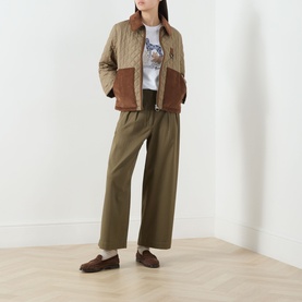 Model wearing Barbour Aylesby Quilted Jacket in Dusky Green with brown corduroy collar and pockets, styled with khaki wide-leg trousers and loafers