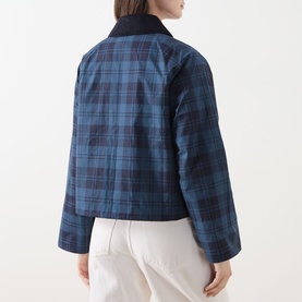 Model wearing Barbour Baiton Check Print Jacket in Weathered Marine, tonal plaid pattern with corduroy collar, back view, styled with white trousers.