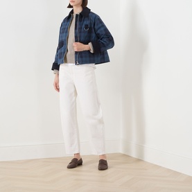 Model wearing Barbour Baiton Check Print Jacket in Weathered Marine with white wide-leg trousers and brown loafers.