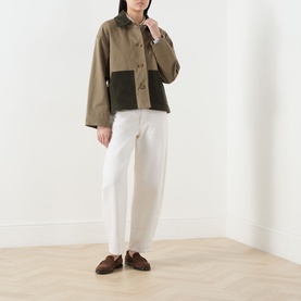 Model wearing Barbour Cloverdale Logo Jacket in Dusky Green with dark corduroy collar and patch pockets, styled with white trousers and brown loafers
