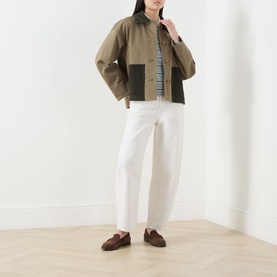 Model wearing Barbour Cloverdale Logo Jacket in Dusky Green with contrasting corduroy collar and patch pockets, styled with white trousers and brown