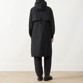 Model wearing Barbour International black hooded longline jacket, shown from rear with wide-leg black trousers and black shoes.