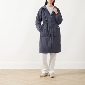 Model wearing Barbour International jacket in Odyssey navy, longline hooded style with drawstring waist, styled with white trousers