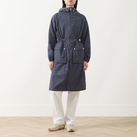 Model wearing Barbour International jacket in Odyssey navy, hooded longline silhouette with drawstring waist and front pockets, styled with white