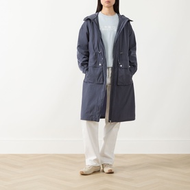 Model wearing Barbour International jacket in Odyssey navy, styled with white wide-leg trousers and grey top, hooded longline silhouette