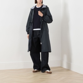 Model wearing Barbour Gracefield Showerproof Jacket in Dark Navy, long parka silhouette with hood, styled with black trousers and white tee.