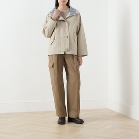 Model wearing Barbour Kingswood Showerproof Jacket in Light Sand with Navy Gingham hood, styled with brown cargo trousers and black loafers.