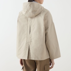 Model wearing Barbour Kingswood Showerproof Jacket in Light Sand, showing back pleat detail and adjustable hood, styled with khaki trousers.