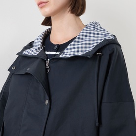 Model wearing Barbour Kingswood Showerproof Jacket in Dark Navy with gingham-lined hood, zip and snap button placket detail visible.