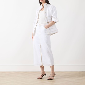 Model wearing Barbour International Kyla Biker Denim Jacket in Denim White with white midi skirt and black strappy heels.